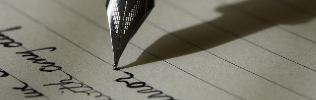 close-up photo of an ink pen writing in cursive letters